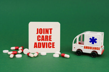 medical concept. On a green surface, an ambulance, pills and a sign with the inscription - joint care adviceの写真素材