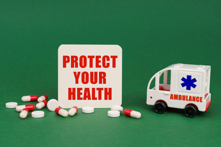 medical concept. On a green surface, an ambulance, pills and a sign with the inscription - PROTECT YOUR HEALTHの写真素材