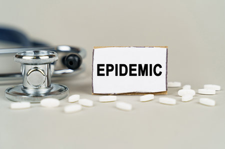 medical concept. On a gray background, a stethoscope, pills and a cardboard plate with the inscription - EPIDEMICの写真素材