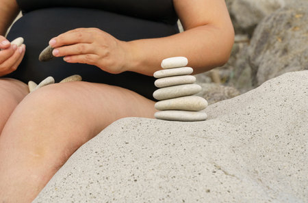 A woman builds a pyramid out of stones. The concept of rest and relaxation.