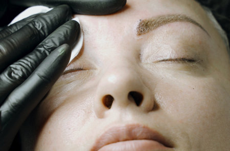 close-up. The beautician cleans the eyebrows of a woman after the microblading procedure.の写真素材