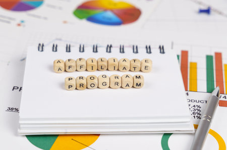 business concept. On the charts with economic indicators are a pen, a notebook and cubes with the inscription - Affiliate programの写真素材