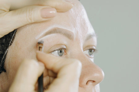 Coloring with white lines the design of the shape of the eyebrows on the face of a woman. microblading. The beauty of a woman.の写真素材