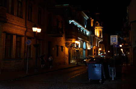 BATUMI, GEORGIA, AJARIA - AUGUST 30, 2022: Old street of Batumi at night, illumination of buildings, traffic of cars and people.のeditorial素材