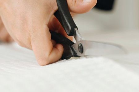 work at home. small business. A woman seamstress cuts a white fabric on the table. close-up.