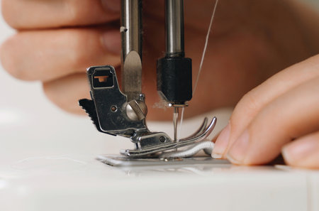 work at home. small business. A female seamstress sews white fabric items on a sewing machine....