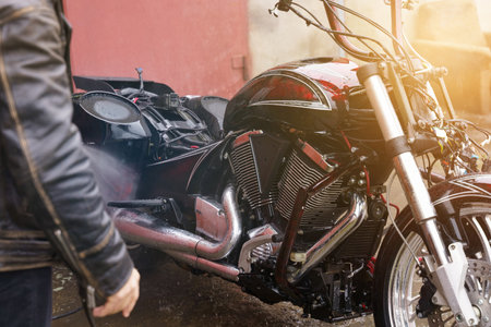 Washing a motorcycle engine with a high pressure jet. close-up.