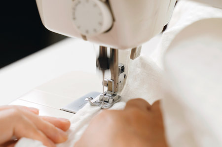 work at home. small business. A female seamstress sews white fabric items on a sewing machine....