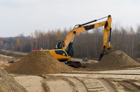 Yellow excavator is working on a sand embankment.