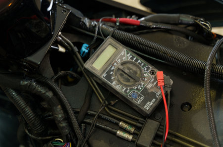 A mechanic using a multimeter checks the voltage level on a motorcycle battery in a garage. close-up