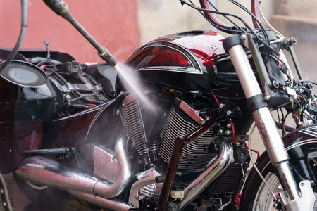 Washing a motorcycle engine with a high pressure jet. close-up.の写真素材