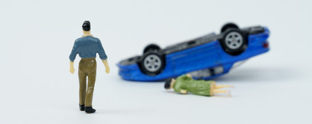 On a white background, a man who is walking towards a car overturned as a result of an accident and a woman lying down.の写真素材
