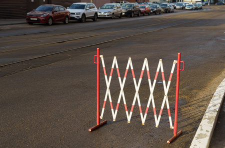 Restrictive temporary fence of red and white color in a parking area on a city street.