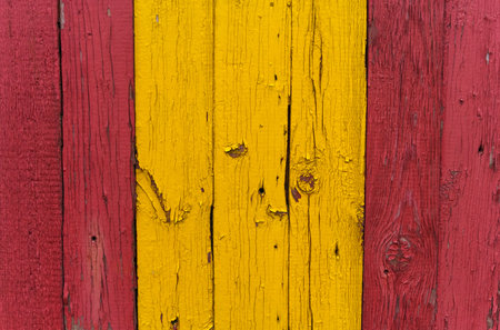 Wooden fence panel with boards painted in red and yellow, close-up.の写真素材