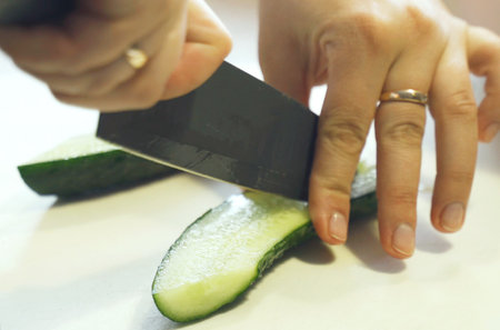 A little boy cuts a cucumber with a knife. close-up.の写真素材