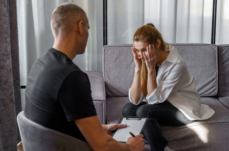 A man psychologist carefully listens to the patient - a woman who emotionally talks about himself, makes notes.の写真素材