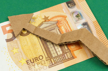 Euro banknotes and a cardboard arrow pointing up lie on a green surface. economic growth.の写真素材
