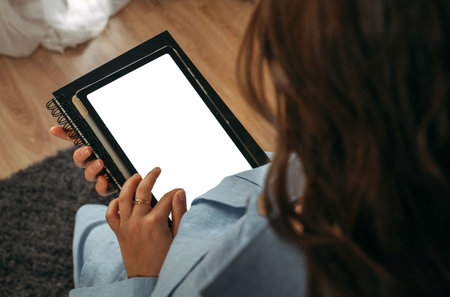 A woman holds a tablet in her hands, on the screen of which there is free space. mockup. view from...