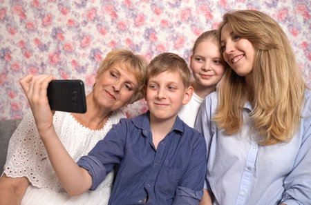 The boy takes a selfie of the family sitting on the sofa in the room.の写真素材