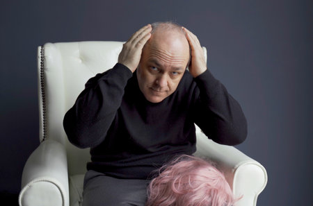 The man is concerned about the problem of hair loss and baldness. He examines his hair on his head.