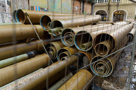 Pipelines of different diameters lie behind a fence on a city street. Reconstruction of communications.の写真素材