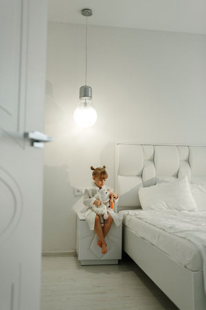 A girl in a bathrobe plays with a knitted unicorn.の写真素材