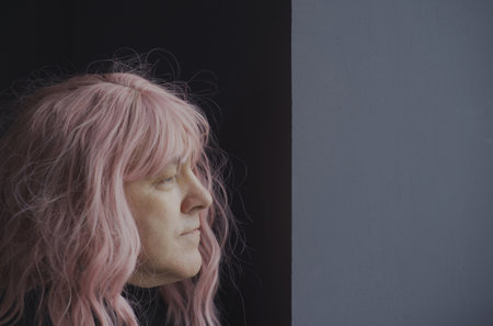 Portrait of a man in a pink wig looking out the window. side view. close-up.