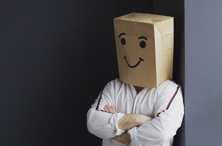 A portrait of a man in a white shirt with a paper bag on his head, with a painted smiley face,...
