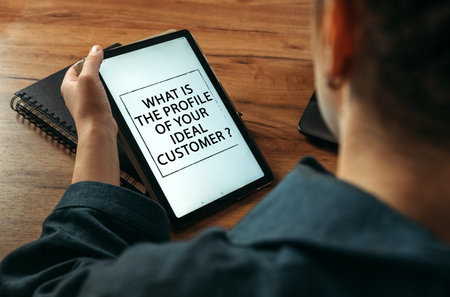 business concept. A woman holds a tablet in her hands on the screen of which it is written - WHAT IS THE PROFILE OF YOUR IDEAL CUSTOMERの写真素材