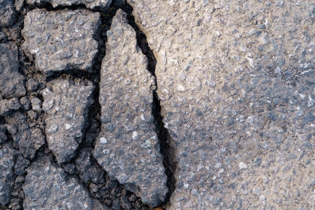 Damaged asphalt on the highway. Close-up of an old road with cracks and damage.の写真素材