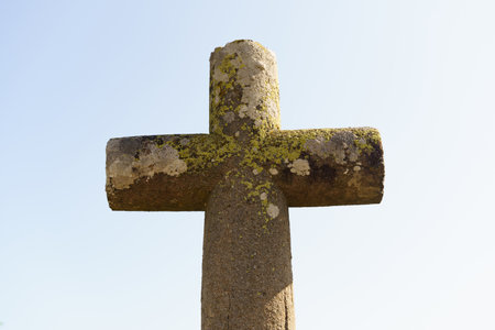 An ancient stone cross under a bright blue sky.の写真素材