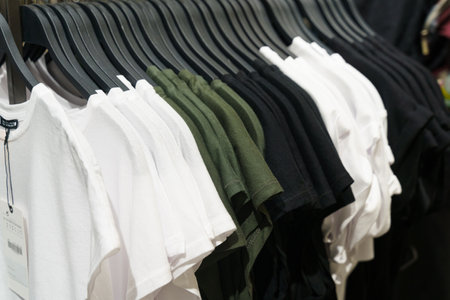 A collection of pastel-colored T-shirts hanging on a clothes rack on a counter in a store. Selective...