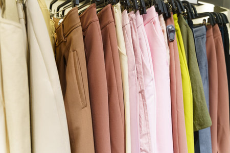 Multi-colored trousers hang on hangers in a women's clothing store. close-up.の写真素材