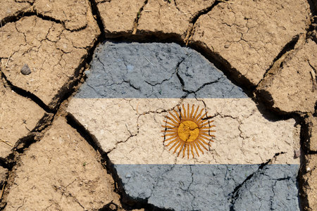 Ecological concept. Drought. On dry, cracked ground, the image of the flag of Argentina.の写真素材