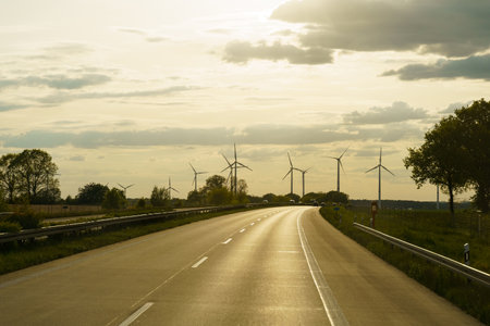 Wind turbines against the backdrop of the setting sun along the road. Alternative energy sources.の写真素材
