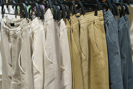 Men's trousers hang on hangers in a clothing store. Close-up, background.