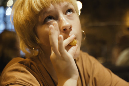 Teen girl eats delicious cheese sticks in a restaurant, enjoying. Close-up.の写真素材
