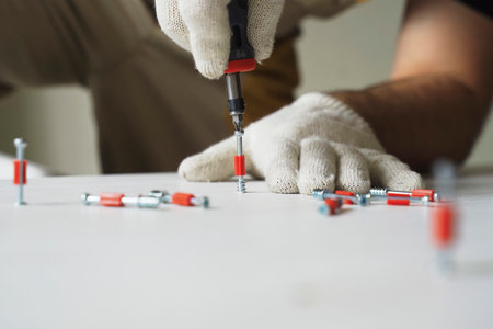 A male worker tightens fasteners on parts of cabinet furniture. Furniture assembly. Close-up.