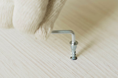 Furniture assembly. A worker fastens the parts of a bed using a confirmat. Close-up.の写真素材