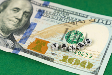 Economics and business. On the US hundred dollar bill there are metal circles with the inscription - Taxesの写真素材