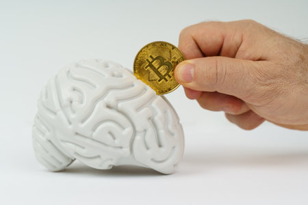 Cryptocurrency concept. On a white background, a model of the brain and Bitcoin in the hands of a person.の写真素材
