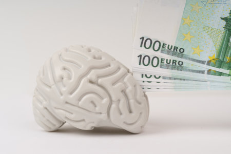 A brain lies on a white background, with a euro in his hand nearby. Smart brain intelligence makes money.の写真素材