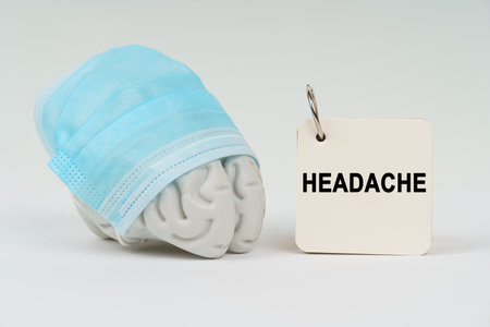 Medical concept. On a white surface next to the brain there is a notepad with the inscription - Headacheの写真素材