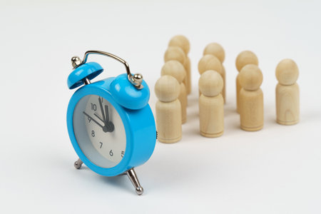 On a white background there is a blue alarm clock behind it, a figure of a man. Business concept.の写真素材