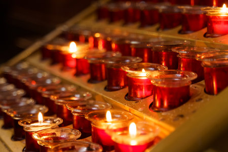 A straight row of red candles placed neatly on a wooden table, each candle emitting a soft glow creating a warm ambiance.の写真素材