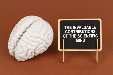 On a brown background, a model of the brain and a sign with the inscription - The invaluable contributions of the scientific mind. Science and education concept.の写真素材