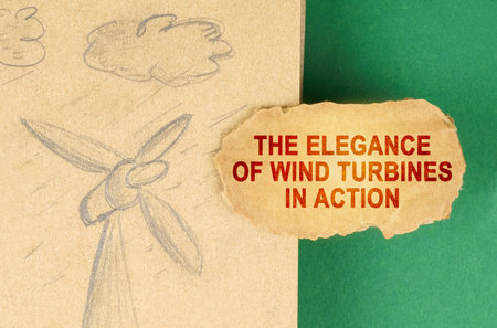 Alternative energy concept. On a green surface there is a drawing with a wind generator and a cardboard with the inscription - The elegance of wind turbines in actionの写真素材