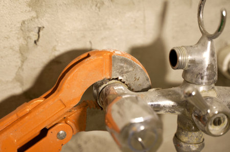 A close-up view capturing the precise moment a wrench grips and tightens a connecting piece on a plumbing installation.の写真素材