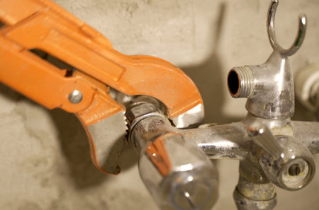 A close-up view capturing the precise moment a wrench grips and tightens a connecting piece on a plumbing installation.の写真素材