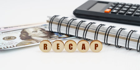 Business and finance concept. On a high surface lie a notepad, a calculator, dollars and wooden...